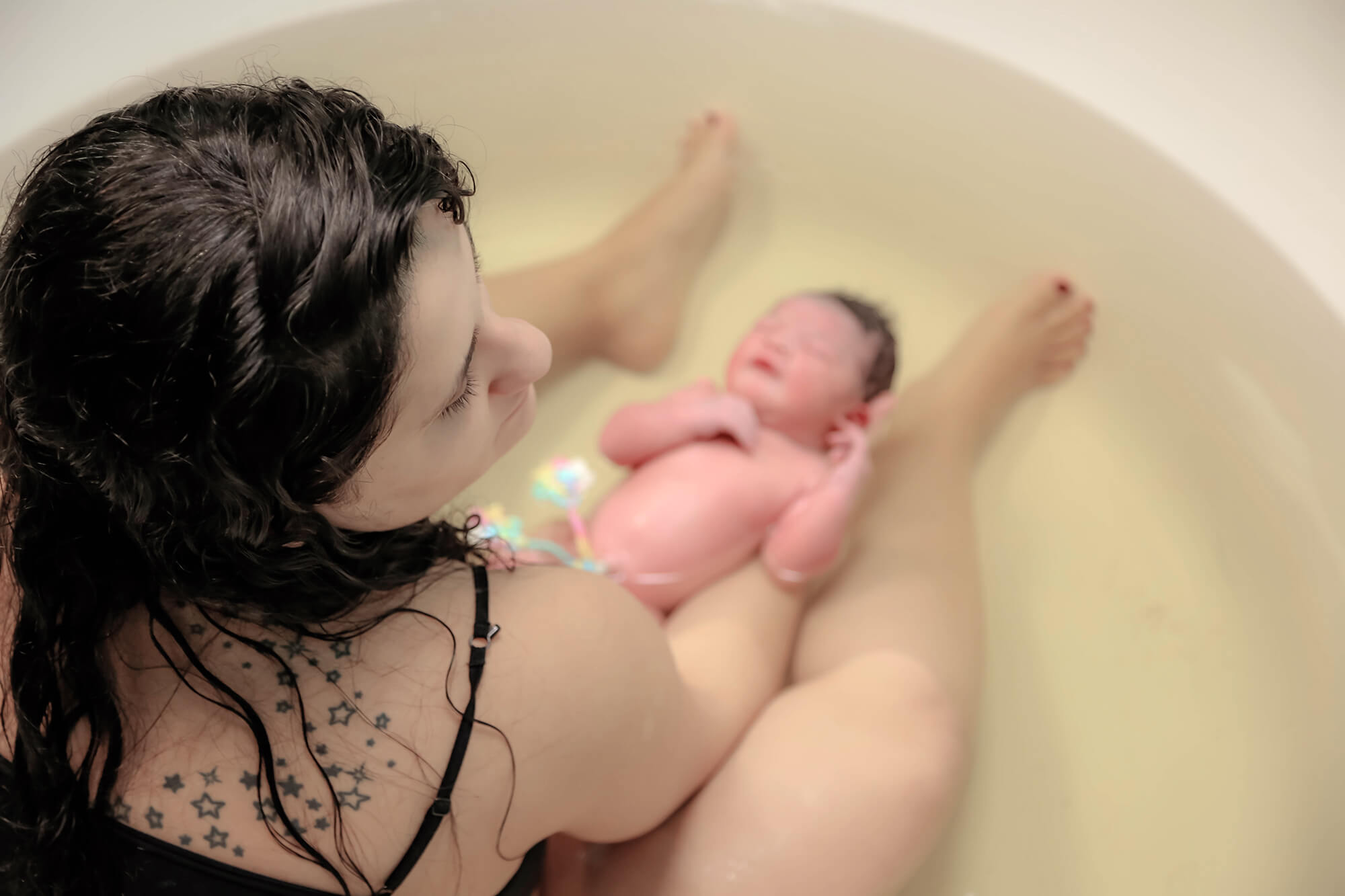 Mom and her newborn baby girl enjoying a hot bath prepared for one of the amazing doulas in Houston