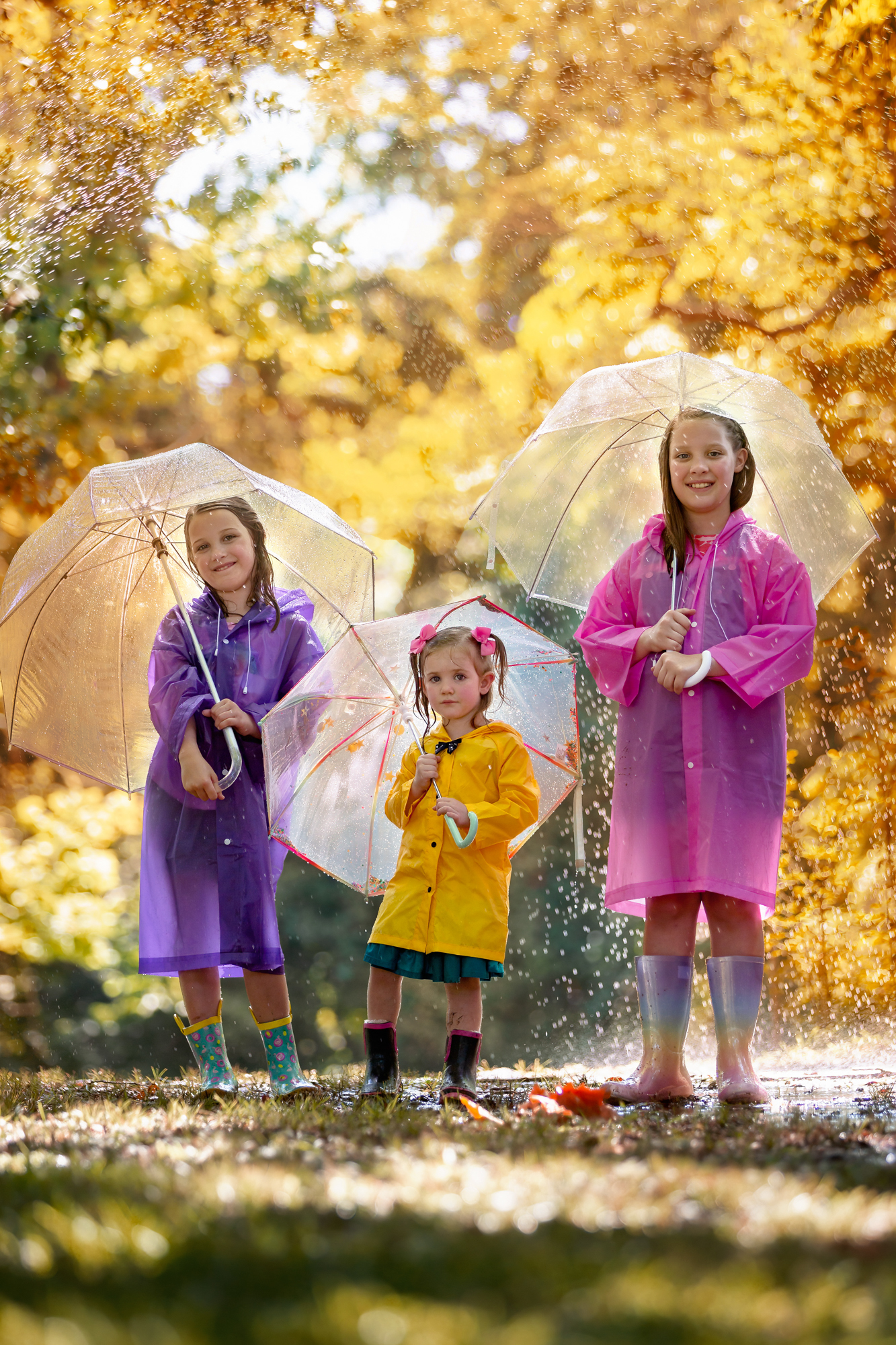 Three sisters holding umbrellas under the pouring rain near one of Houston Pediatricians