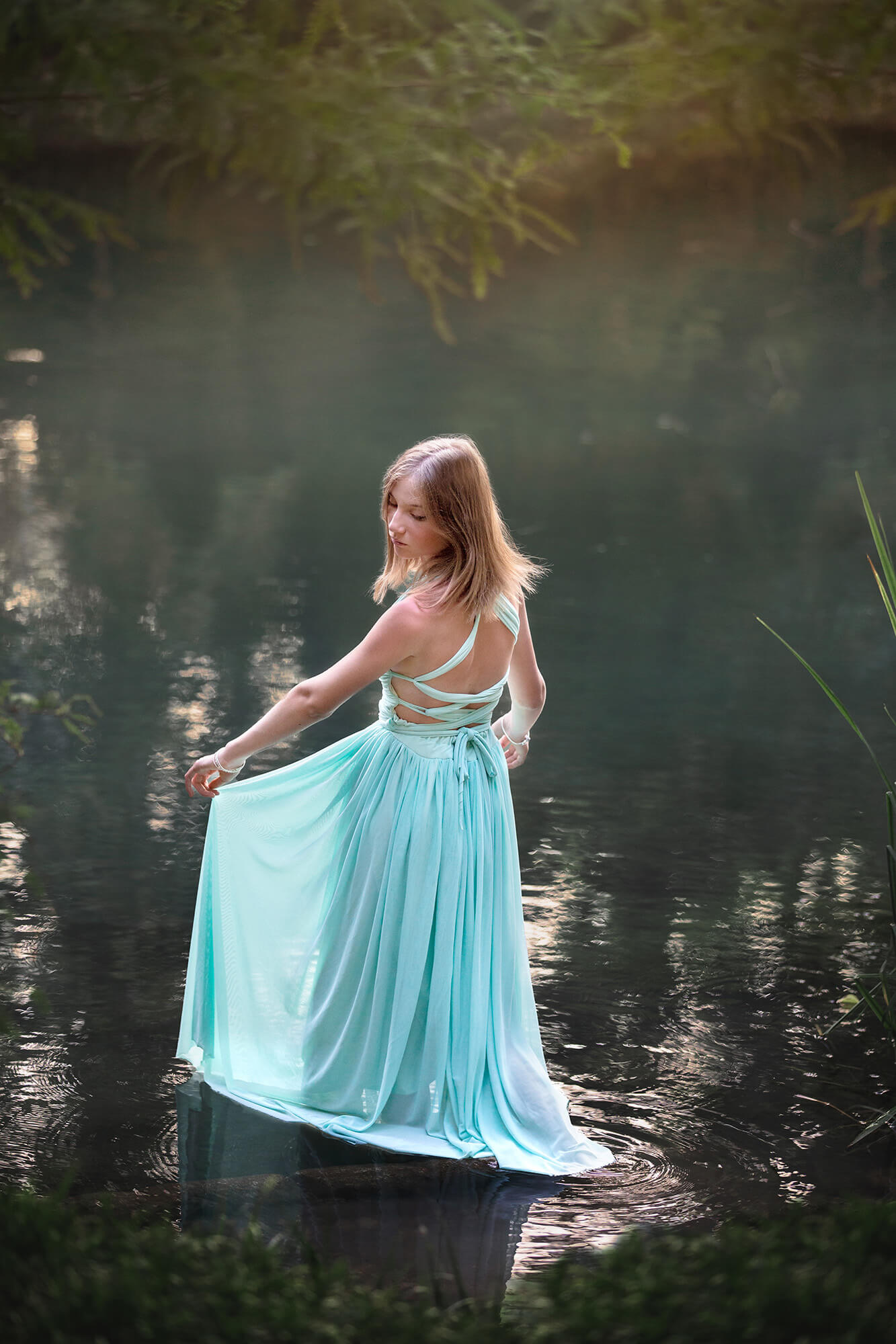 Beautiful teenager girl wearing a blue dress by the Guadalupe river in the Hill Country getaway from Houston, Texas.