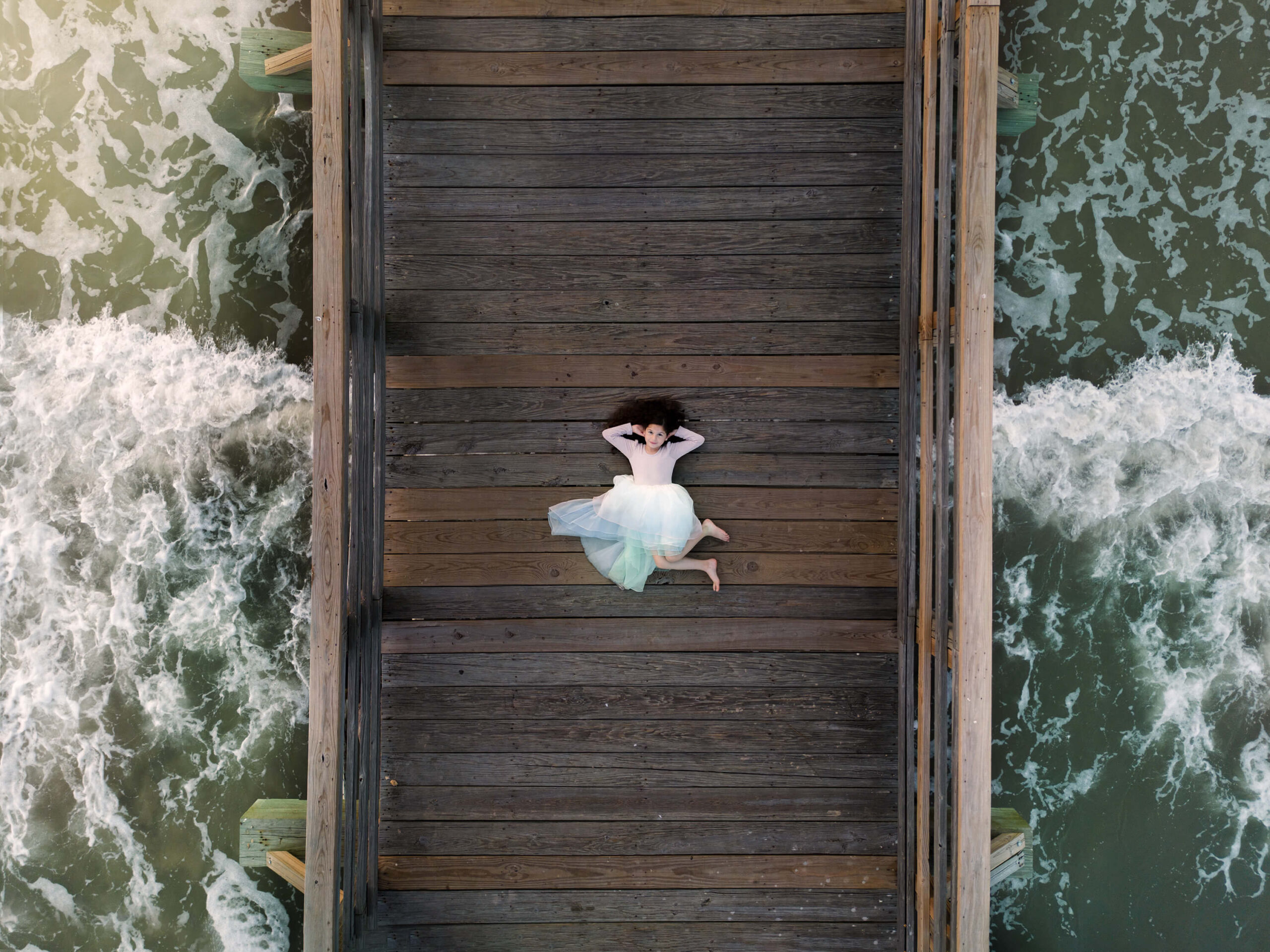 Drone photography of a little girl wearing an ombre dress at the beach showing how you can grow your photography business to the next level.