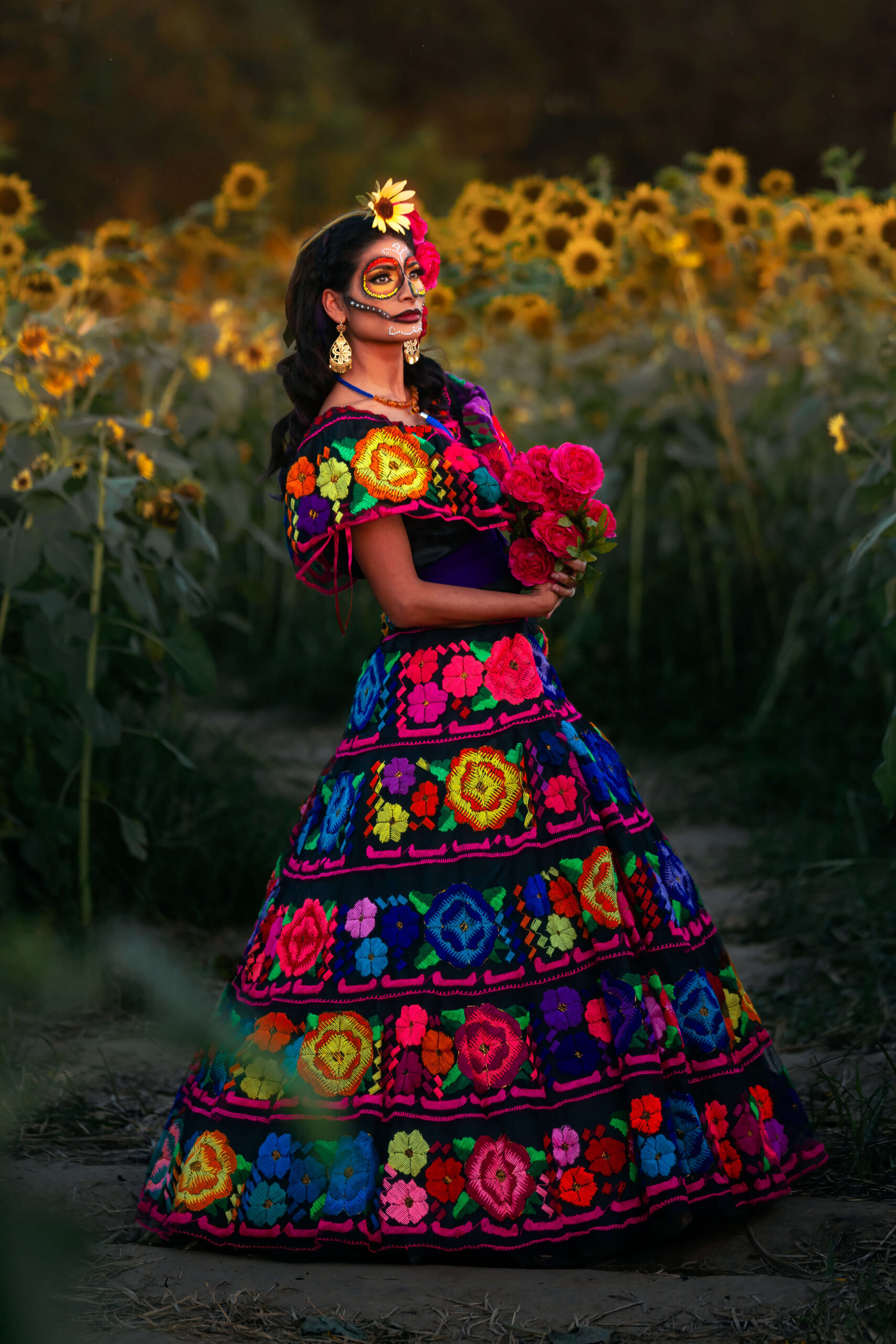 Dark haired lady wearing colorful dress and posing with flowers for Houston obgyn.