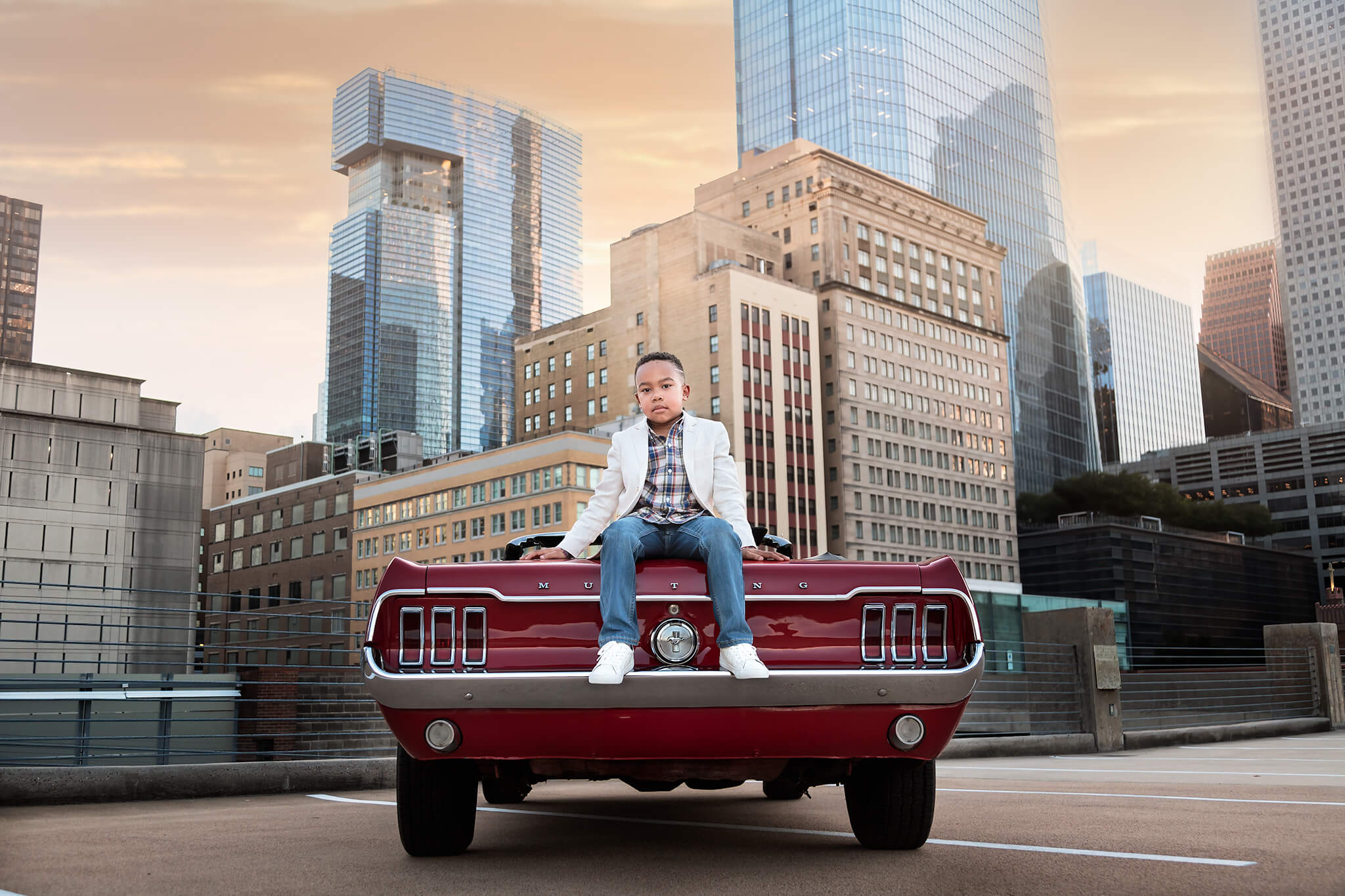 Super stylish boy sitting on the trunk of a vintage car wearing clothes from Zara Houston.